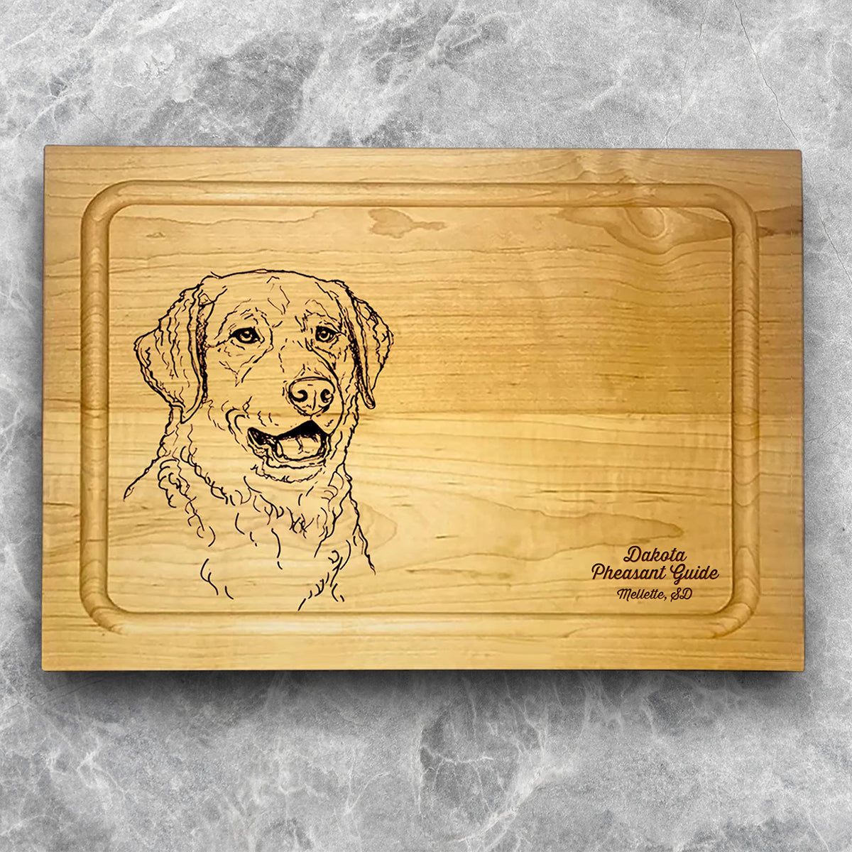 A high-quality, durable maple cutting board with juice groove featuring a laser-engraved Chesapeake Bay Retriever. A perfect addition for any kitchen, and a wonderful reminder of your love of hunting and sporting dogs. A Dakota Pheasant Guide souvenir.