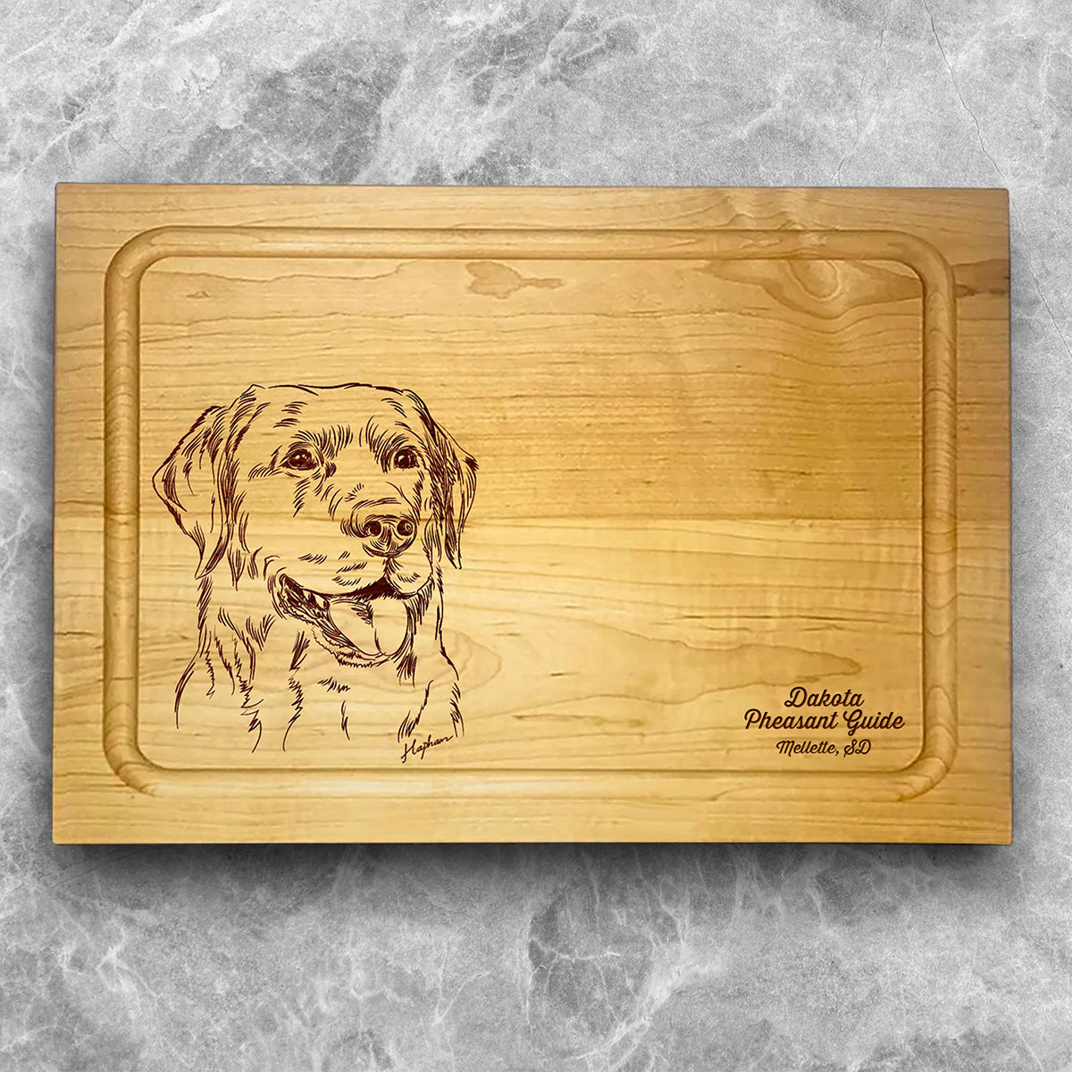 A high-quality, durable maple cutting board with juice groove featuring a laser-engraved Labrador Retriever. A perfect addition for any kitchen, and a wonderful reminder of your love of hunting and sporting dogs. A Dakota Pheasant Guide souvenir.