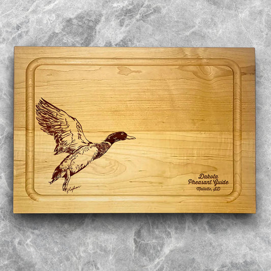 A high-quality, durable maple cutting board with juice groove featuring a laser-engraved Mallard Duck taking flight. A perfect addition for any kitchen, and a wonderful reminder of your love of hunting and game birds. A Dakota Pheasant Guide souvenir.