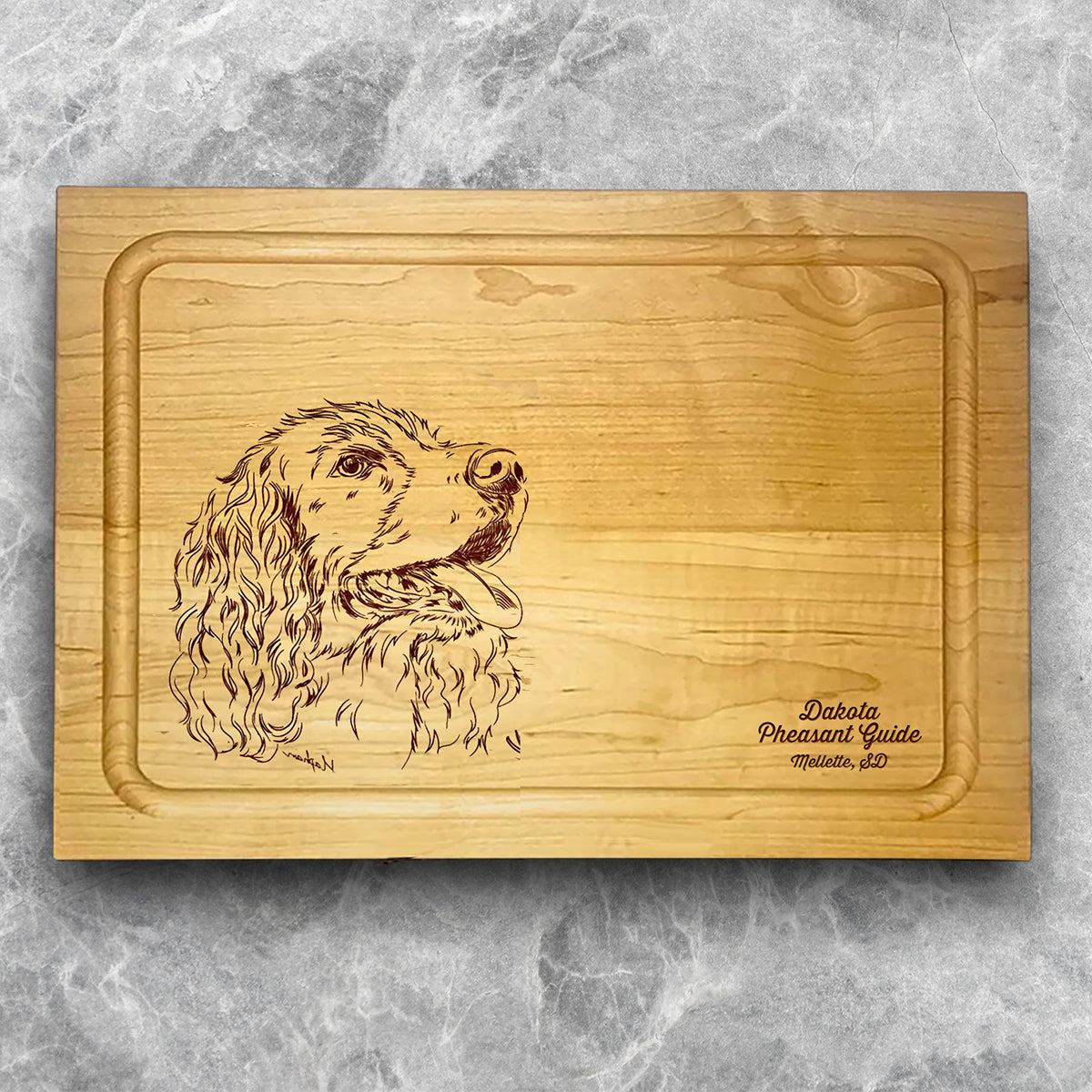 A high-quality, durable maple cutting board with juice groove featuring a laser-engraved Springer Spaniel. A perfect addition for any kitchen, and a wonderful reminder of your love of hunting and sporting dogs. A Dakota Pheasant Guide souvenir.