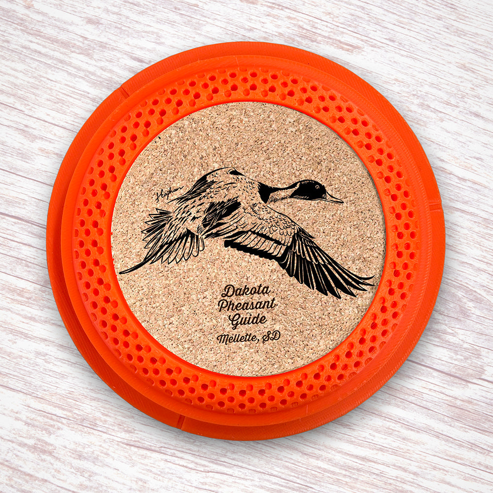 Clay Pigeon shaped coaster base with laser-engraved cork inserts featuring a Pintail Duck - this set of 4 coasters makes a unique gift for any trap shooter, gun enthusiast and game bird lover! By Muggins Gifts for the Dakota Pheasant Guide Souvenir shop.