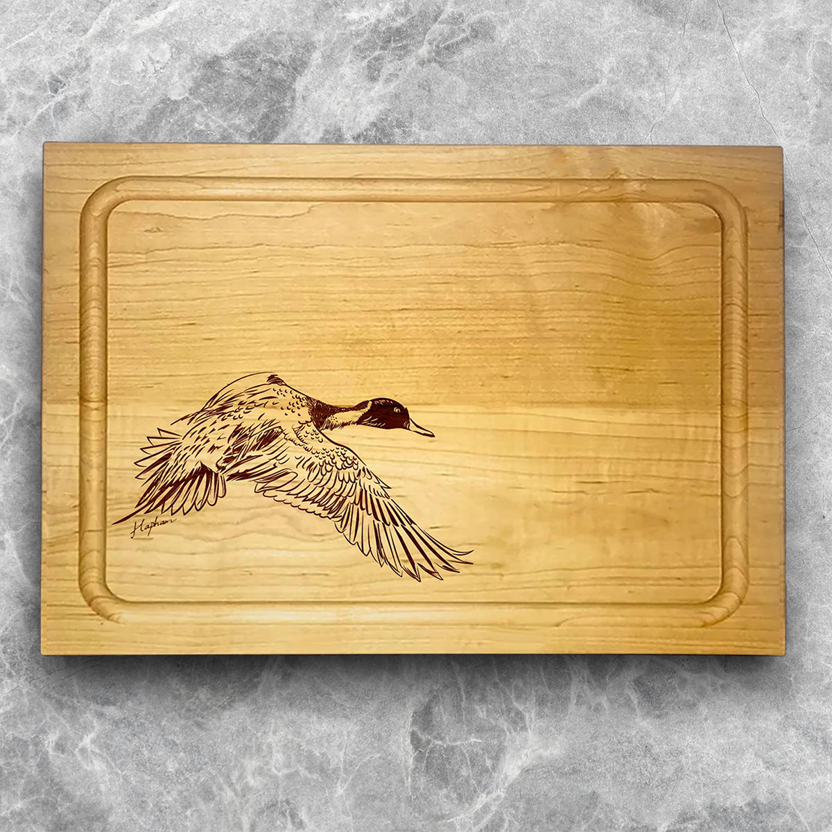 A high-quality, durable maple cutting board with juice groove featuring a laser-engraved Pintail Duck in flight. A perfect addition for any kitchen, and a wonderful reminder of your love of hunting and game birds. A Dakota Pheasant Guide souvenir.