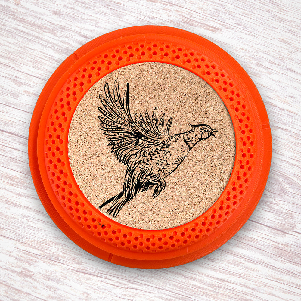 Clay Pigeon shaped coaster base with a laser-engraved cork insert featuring a Pheasant taking flight - this set of 4 coasters makes a unique gift for any trap shooter, gun enthusiast and bird dog lover! By Muggins Gifts for the Dakota Pheasant Guide Souvenir shop.